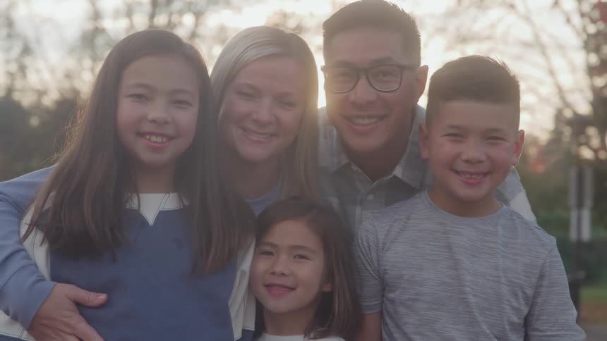 A happy family poses outdoors for a portrait at sunset