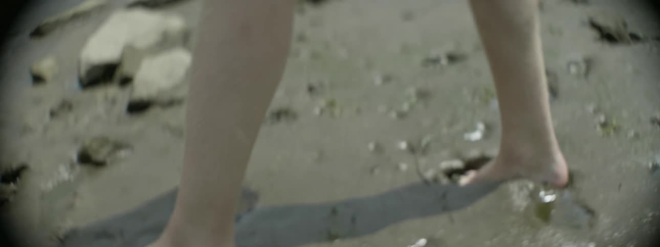 A barefoot man walks in mud