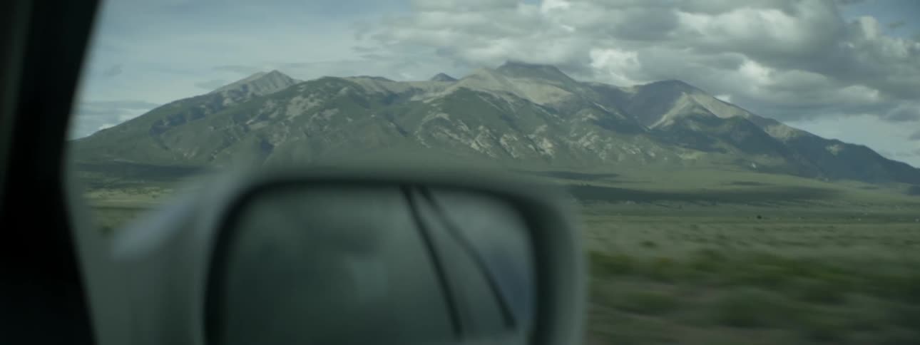 Car traveling near mountains on cloudy day
