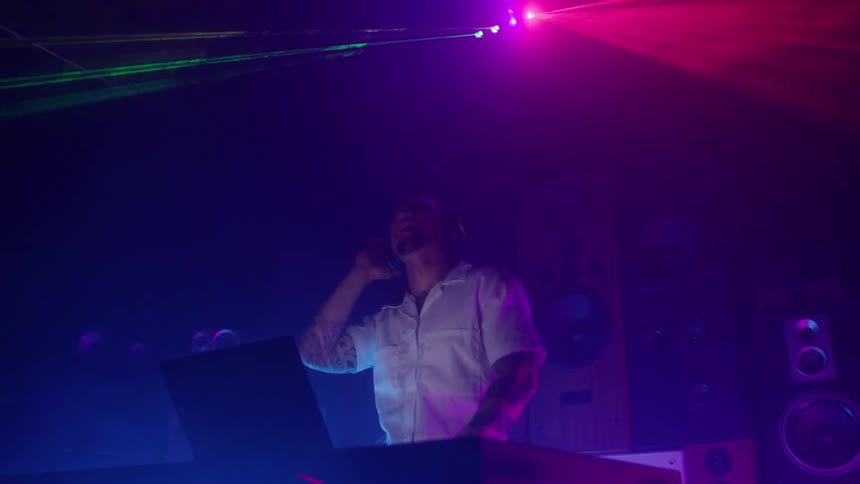 Dj controls the dance floor under colorful lights and laser beams