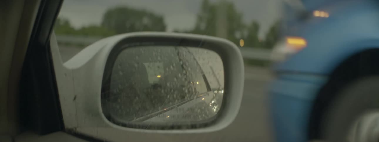 A sideview mirror on a moving vehicle is shown