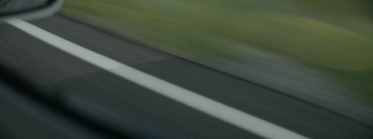 Moving fast down a road there is green grass on the side