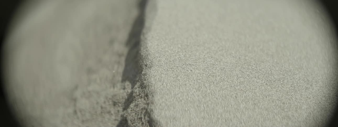 A close up view of sand that is being blown and falling slightly