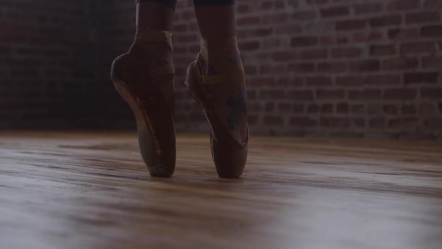 Close up of a female ballet dancer dancing on her tip toes in a room during daytime