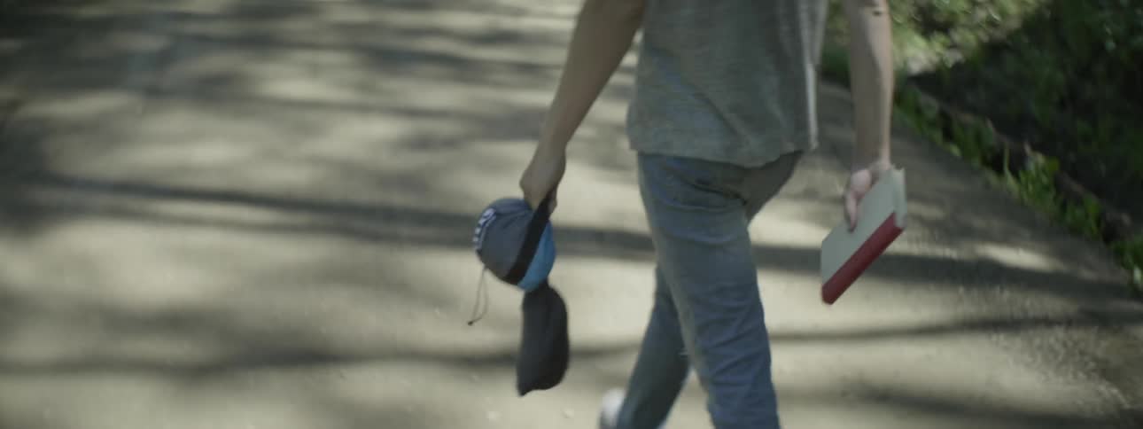A man carries a book and other items outside
