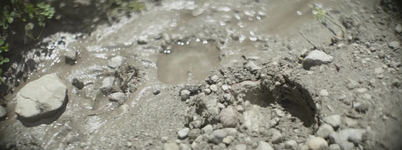 Dray clay dirt hill with holes and one of them is filled with water