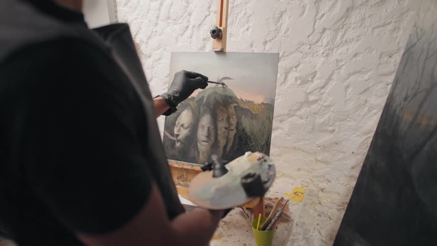 A person is painting on a canvas set up on an easel in a studio