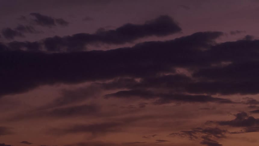 Sky with dense clouds in shades of purple orange and blue during nightfall