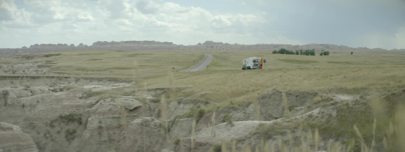 A truck with a camper drives in the wilderness