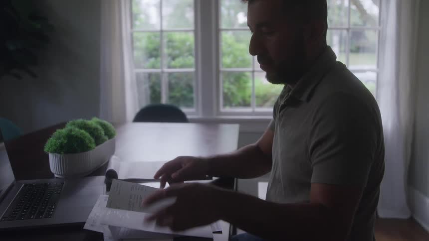 Man sitting at a table reviews documents in natural window light
