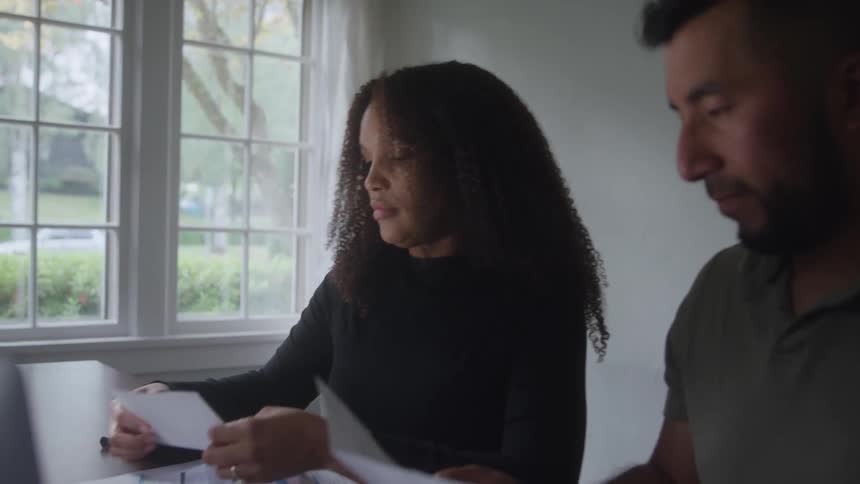 A woman showing a piece of paper to a man and saying something to him