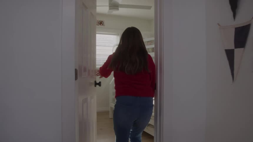 Girl in red blouse enters room and closes door