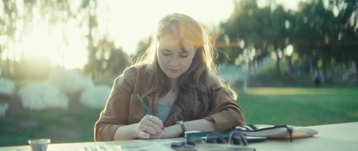 The woman is sketching in the park on a sunny day