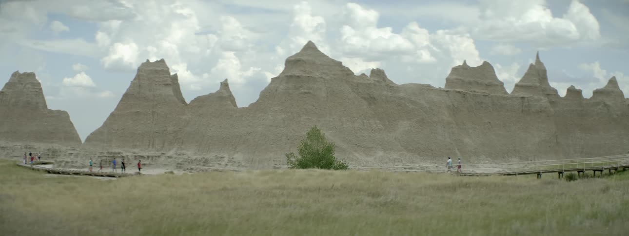 People walk in front of a large rock formation