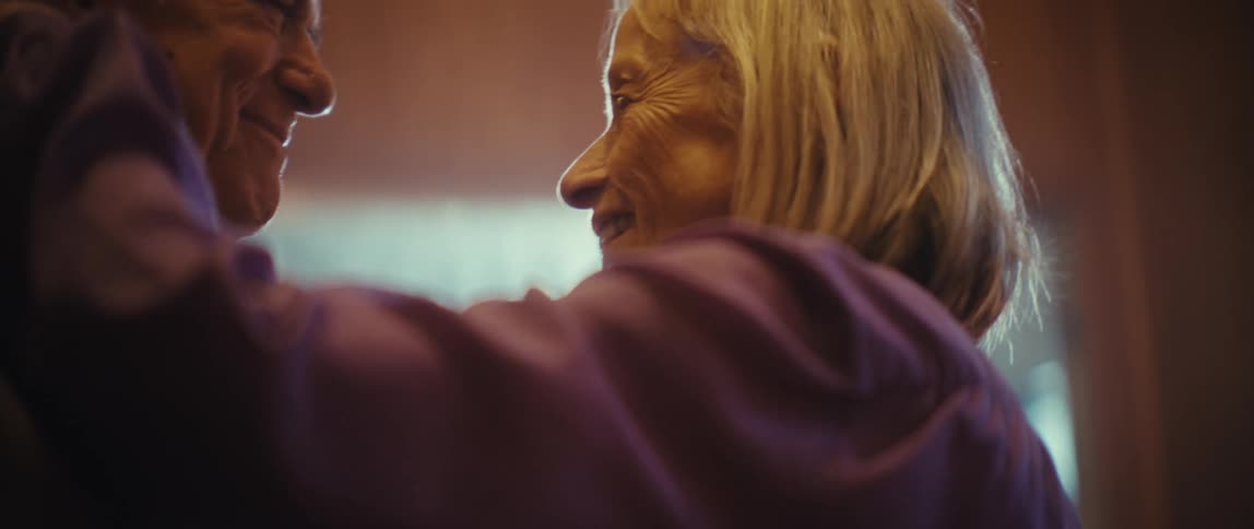 Elderly couple dancing with joyful smiles under soft light