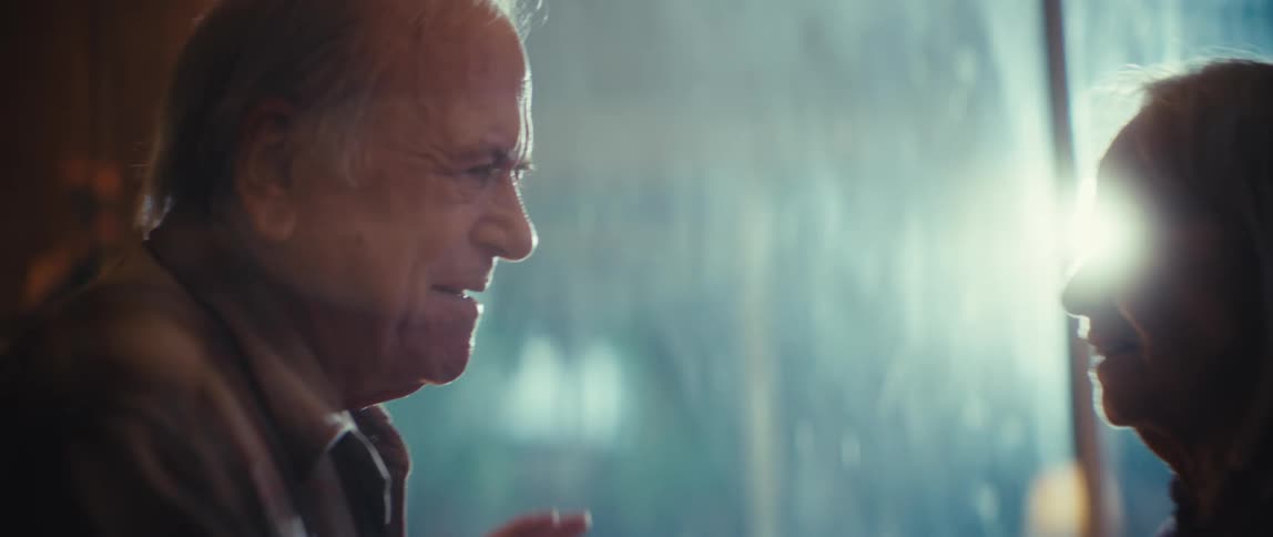 Elderly couple dancing near the window on a rainy day