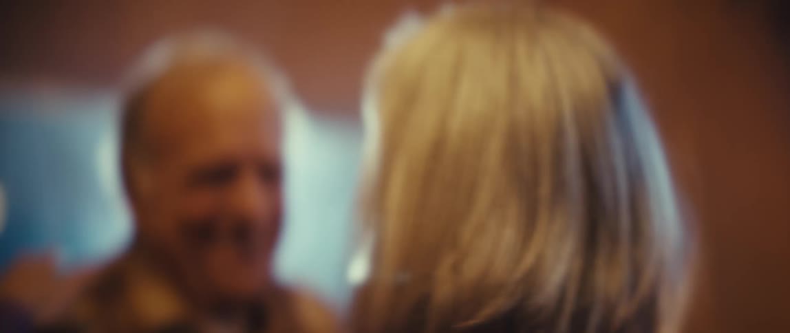 An elderly couple is dancing and smiling