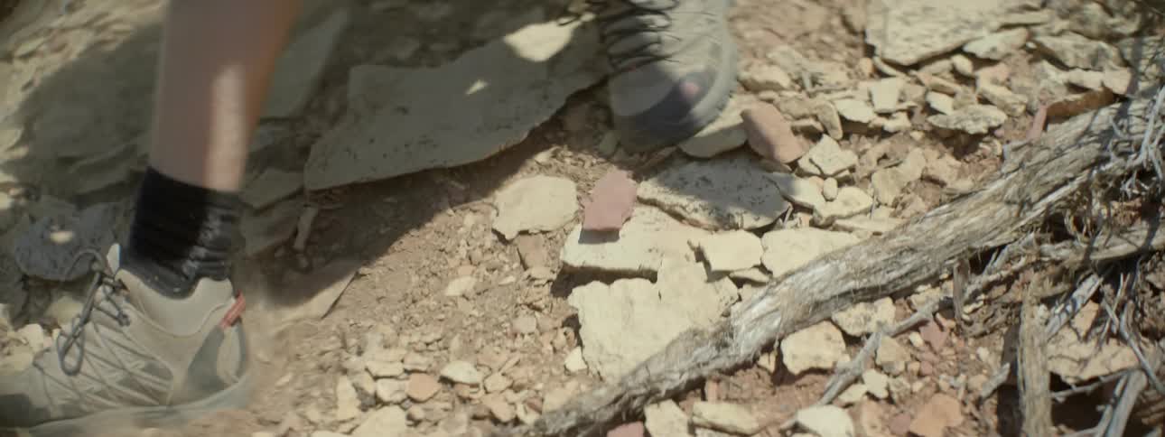 A person is walking downhill over rocks