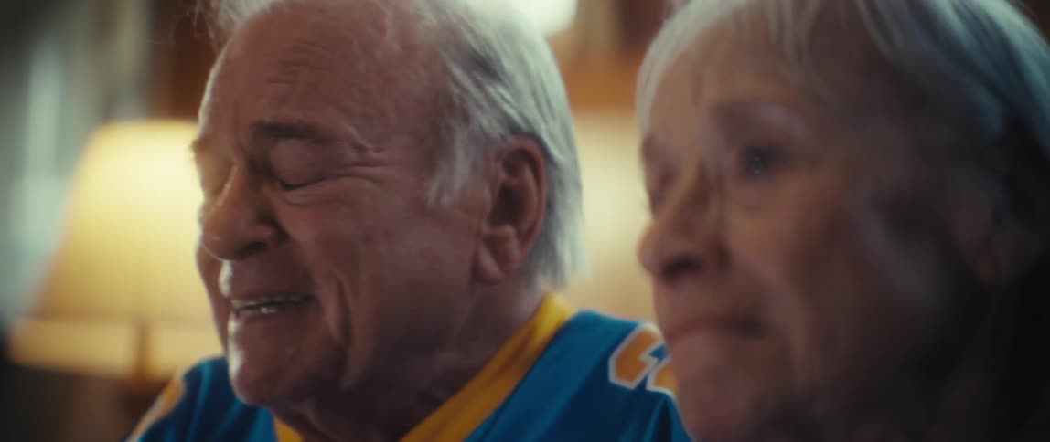 An elderly man and woman watching something feeling sad and crying