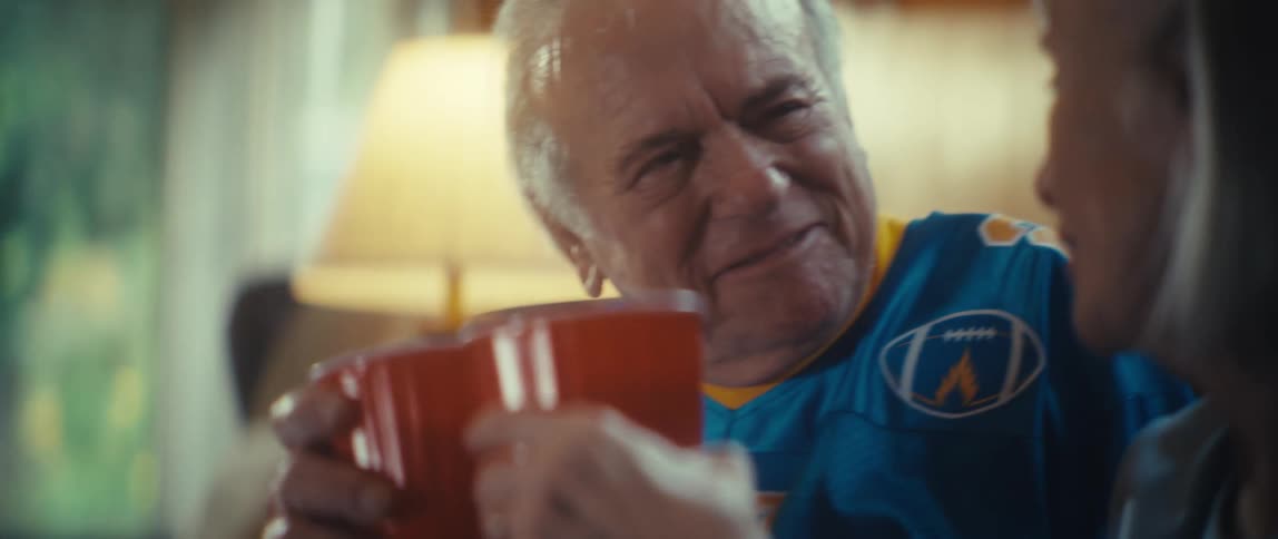 A man and woman pick up cups then toast and drink