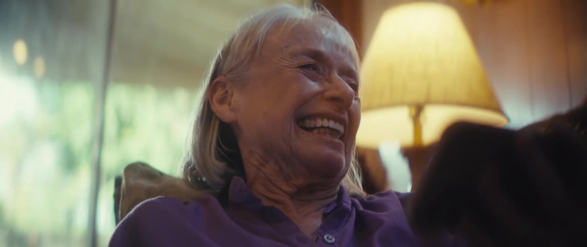 A woman is laughing as she looks at her cellphone