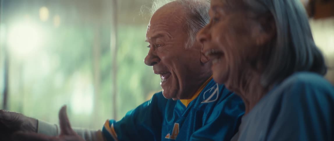 Elderly couple smiling and cheering while watching tv