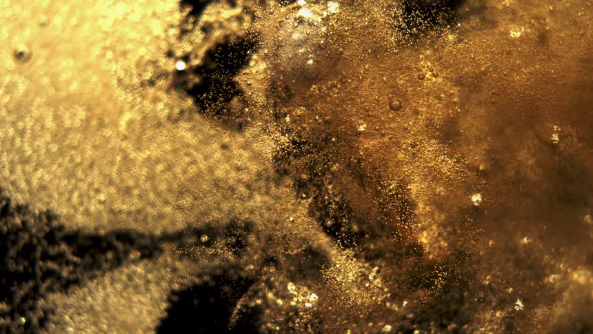 A gold liquid bubbles up and scatters