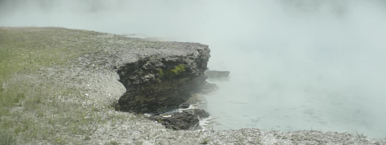 Steam rises from a pool in a natural setting