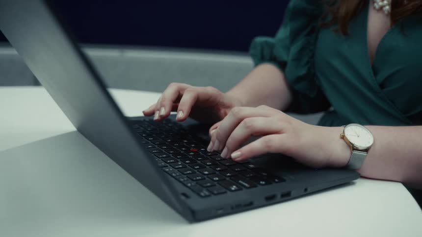 Closeup of a woman typing on a keyboard laptop
