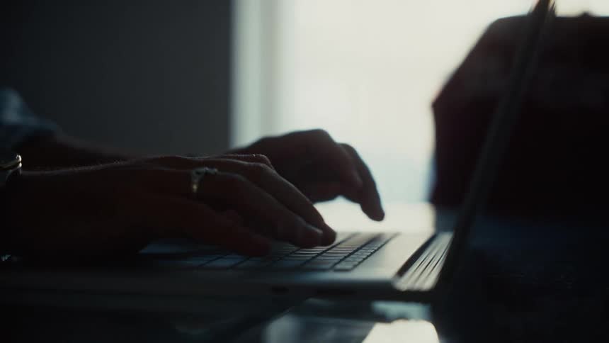 Hands typing on a laptop under soft light