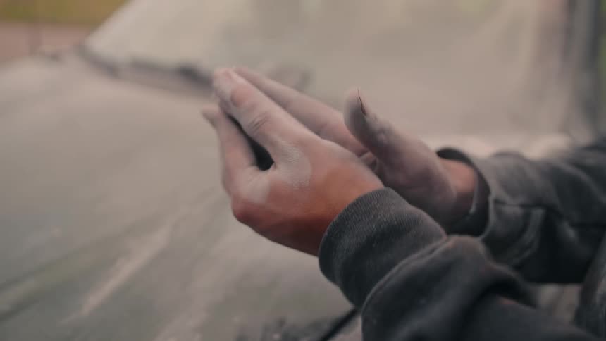 Dust flies as the man claps his hand