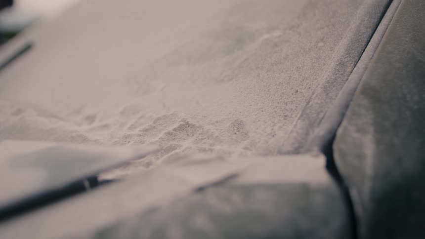 Car hood and windshield covered by thick layer of dust with partially visible wipers