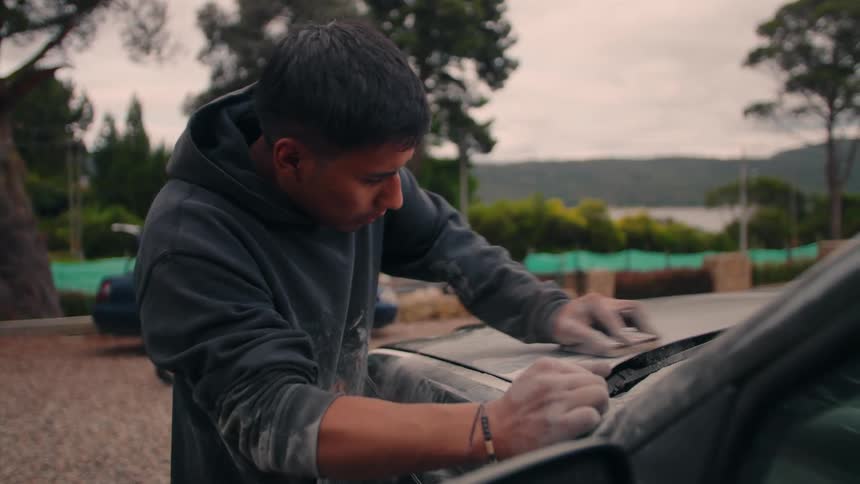 Person sands car surface with hand block