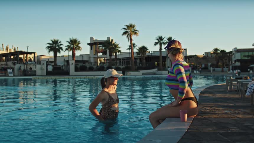 Two two women stretch by the pool