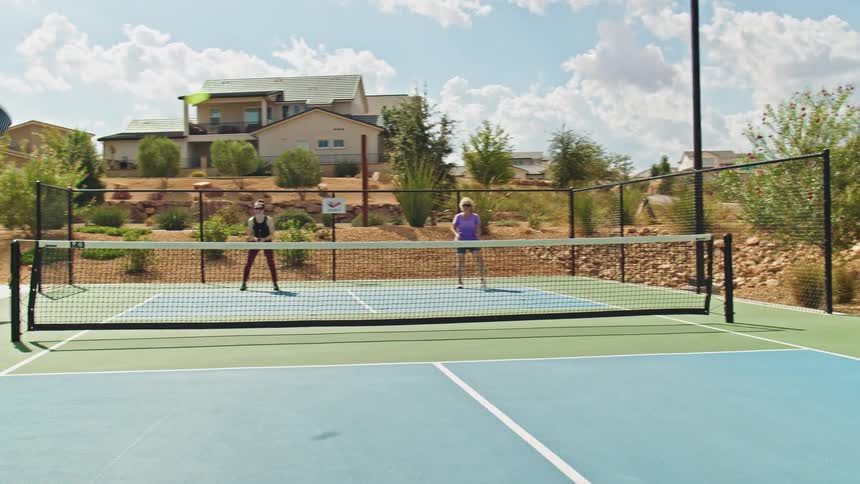 Pickleball game on an outdoor court under a sunny sky