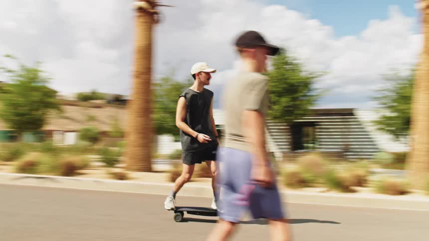 Father and his older son skateboard into an intersection while his younger son watches