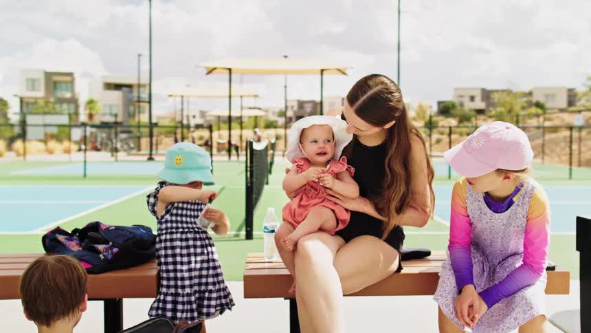 Woman takes care of children while they rest near a sports court