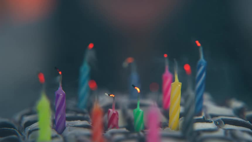 Colorful candles partly extinguished releasing smoke over a cake