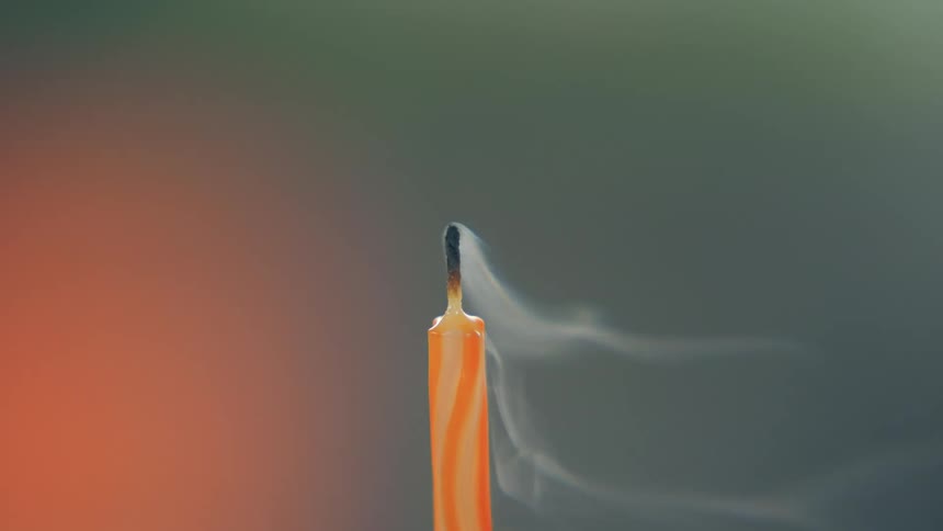 Orange candle wick releasing smoke after being extinguished
