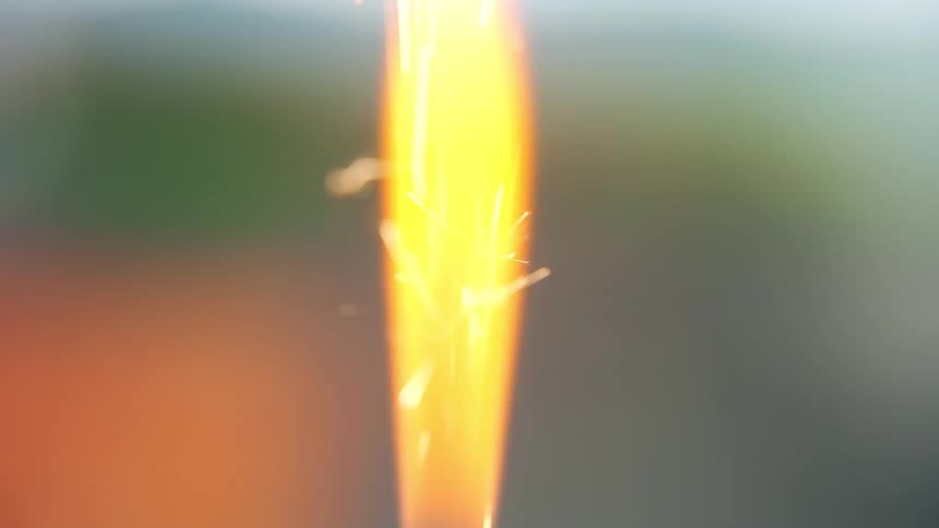 Orange torch emits sparks against a dark background