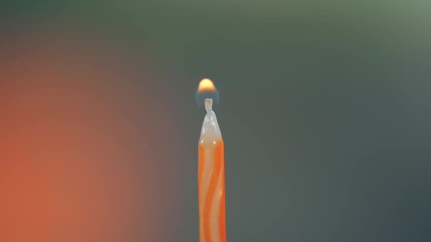 Match flame lighting an orangestriped candle