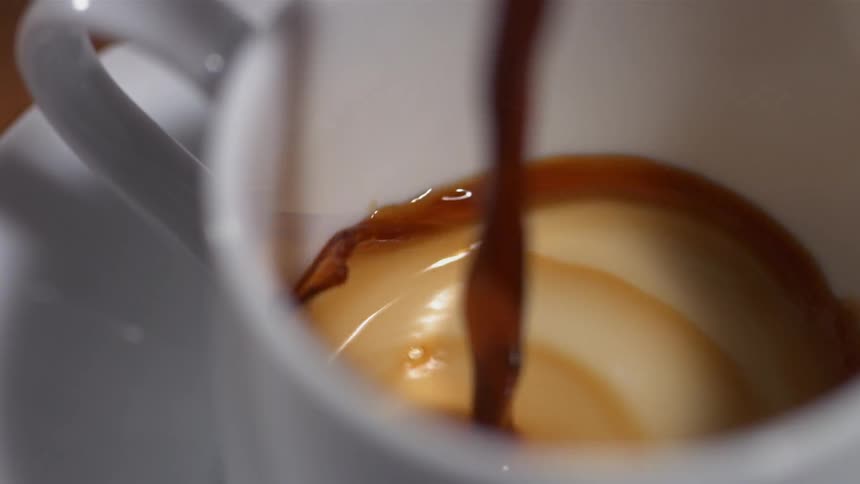 Coffee is poured into a white cup