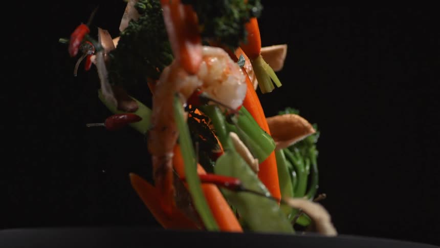 Vegetables and seafood are tossed in a pan