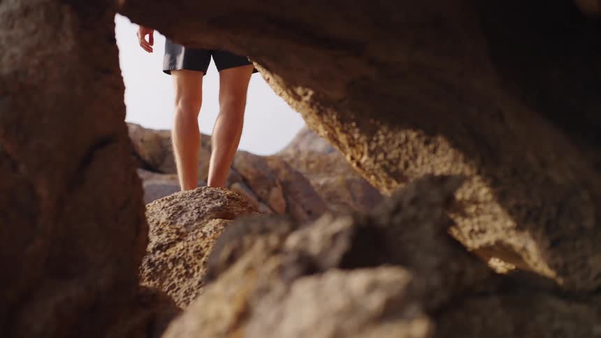 Person walks across rocky terrain framed by natural formations