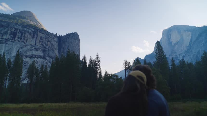 A couple stands together overlooking rocky cliffs at dusk