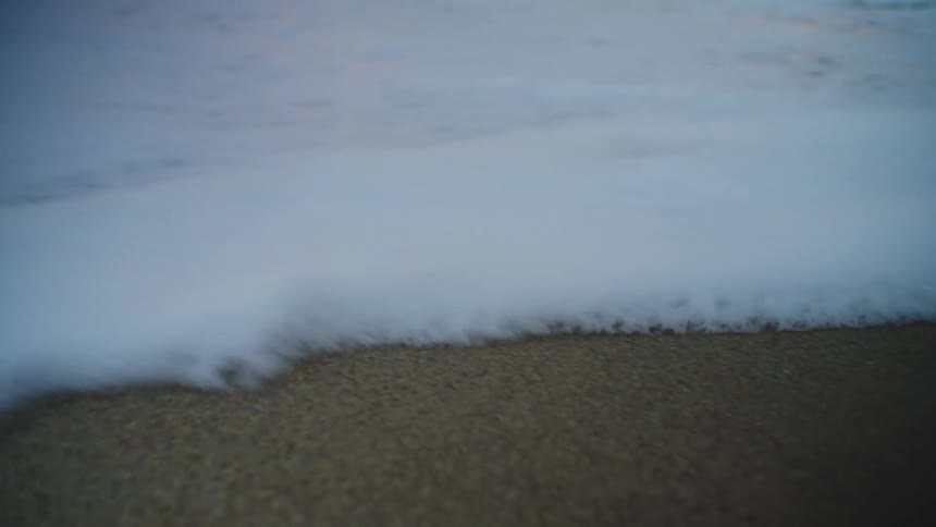 Wave and sea foam roll over the sand on the beach