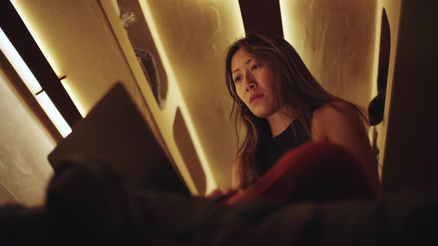 Woman focused on a laptop in a warmly lit room