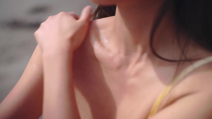 Woman with yellow strap gently touches shoulder in outdoor setting with blurred background and natural light