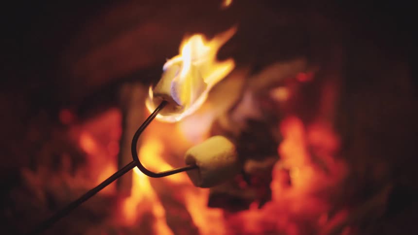 Marshmallows catch fire as they are being roasted over a campfire