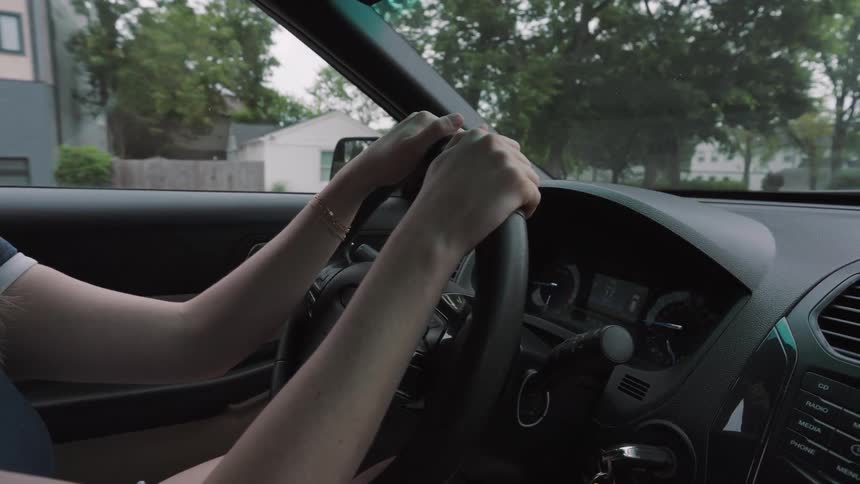 A woman is driving a car through a neighborhood